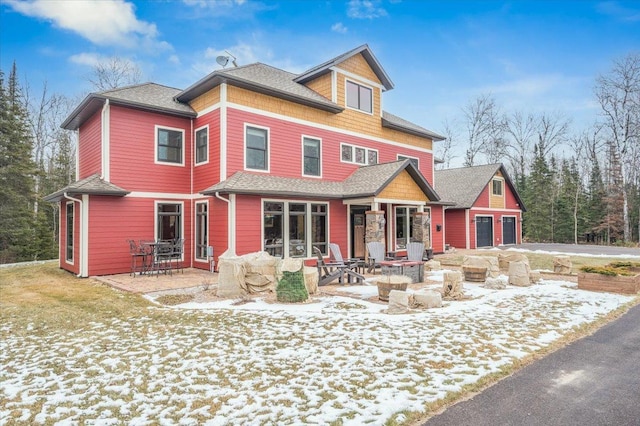 view of front facade featuring a patio, an outdoor fire pit, and a shingled roof