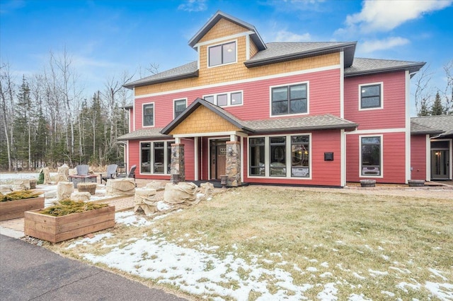 view of front of home featuring a garden, a shingled roof, and a front yard