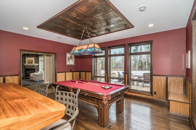 rec room with a wainscoted wall, hardwood / wood-style flooring, a fireplace, and an ornate ceiling