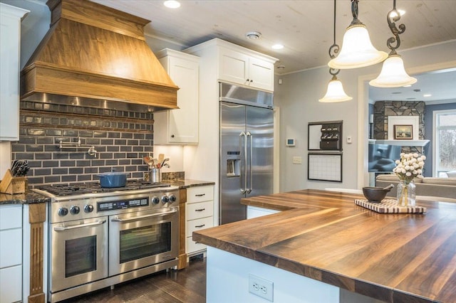 kitchen with custom range hood, appliances with stainless steel finishes, crown molding, wooden counters, and backsplash