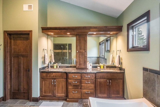 full bathroom with double vanity, visible vents, vaulted ceiling, a shower stall, and a sink