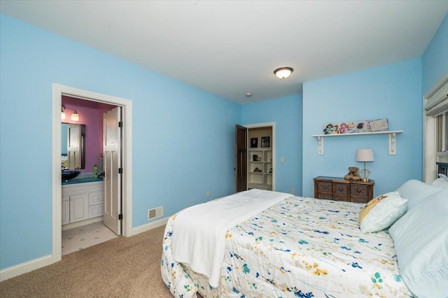 carpeted bedroom with visible vents, baseboards, and ensuite bathroom