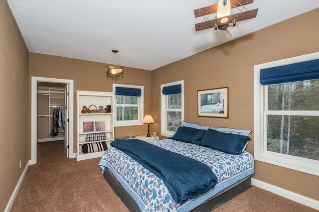 bedroom featuring a walk in closet, a closet, baseboards, and carpet