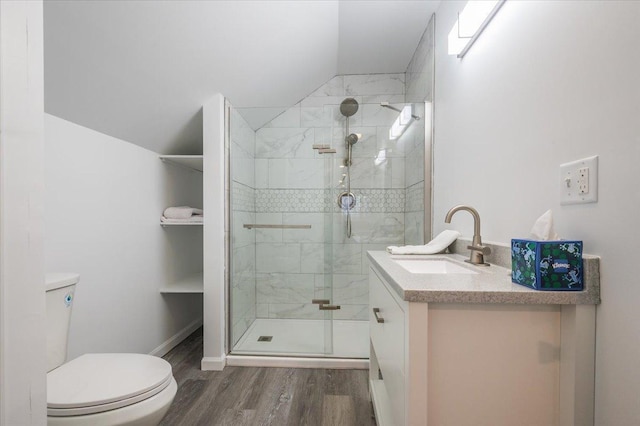 bathroom with a stall shower, toilet, wood finished floors, vaulted ceiling, and vanity