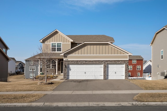 craftsman inspired home with aphalt driveway, stone siding, board and batten siding, and an attached garage