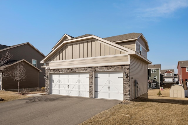 exterior space with a storage unit, driveway, stone siding, board and batten siding, and an outdoor structure