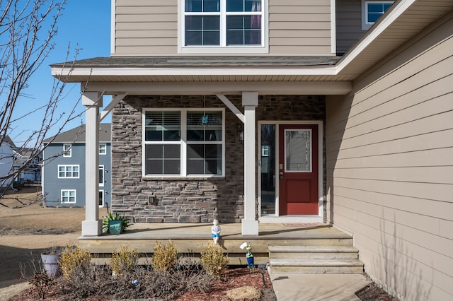 doorway to property with a porch and stone siding