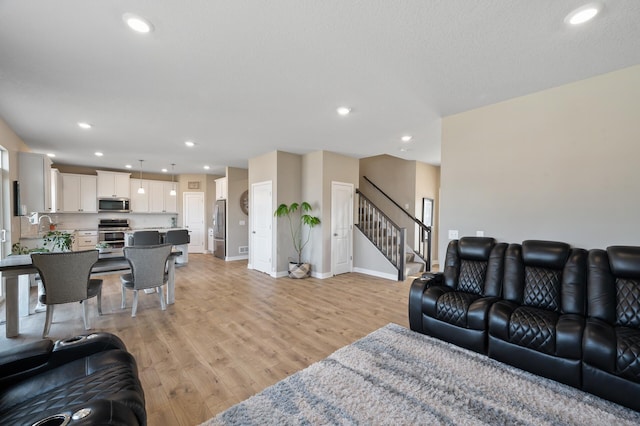 living area featuring recessed lighting, stairs, and light wood finished floors