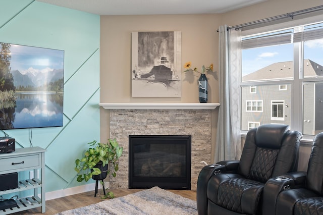 living room featuring a stone fireplace, wood finished floors, and baseboards