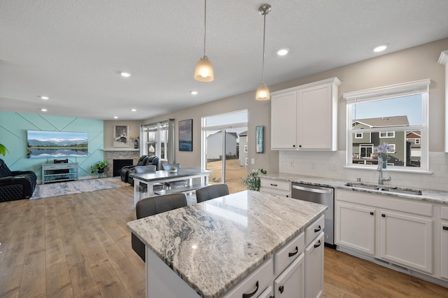 kitchen featuring stainless steel dishwasher, a center island, tasteful backsplash, and a sink