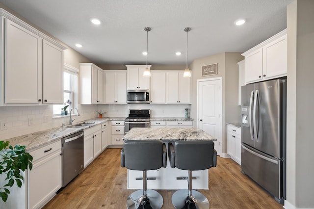 kitchen featuring decorative backsplash, white cabinets, stainless steel appliances, and a sink