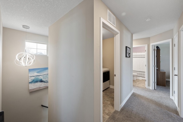 corridor with visible vents, baseboards, a chandelier, carpet floors, and a textured ceiling