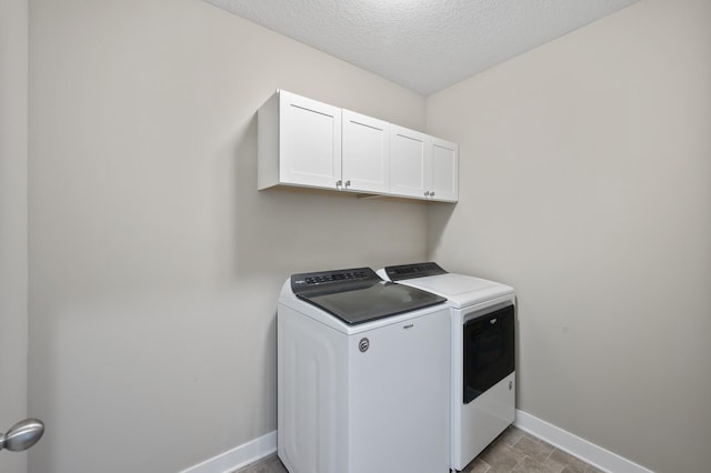 clothes washing area featuring cabinet space, washing machine and dryer, a textured ceiling, and baseboards