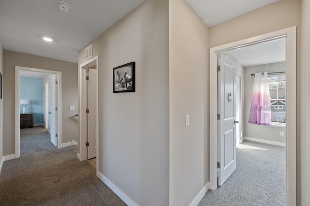 hallway featuring carpet flooring, baseboards, and visible vents