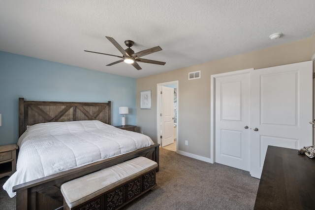 carpeted bedroom featuring baseboards, visible vents, ensuite bath, ceiling fan, and a textured ceiling