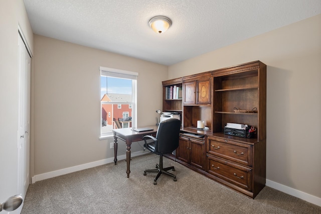 carpeted home office featuring baseboards and a textured ceiling