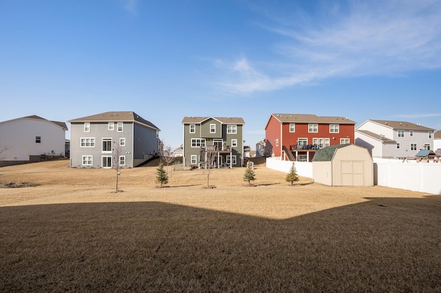 view of yard featuring a residential view, a storage unit, an outdoor structure, and fence