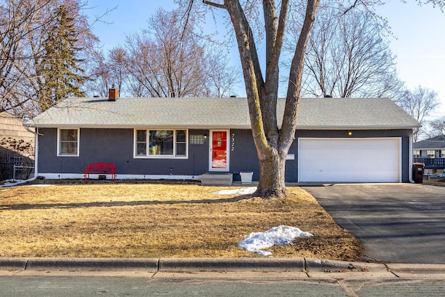 ranch-style home featuring aphalt driveway, a shingled roof, a front yard, an attached garage, and a chimney