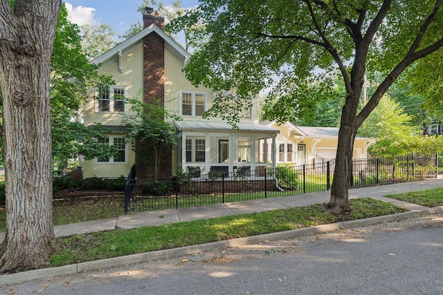 view of front of house featuring a chimney, stucco siding, concrete driveway, a garage, and a fenced front yard