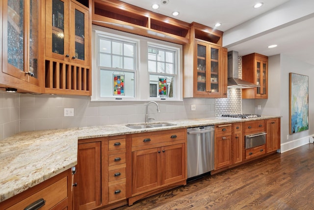 kitchen featuring a sink, brown cabinets, appliances with stainless steel finishes, wall chimney exhaust hood, and dark wood-style flooring