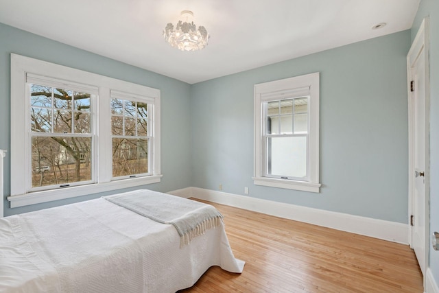 bedroom with a chandelier, baseboards, and wood finished floors