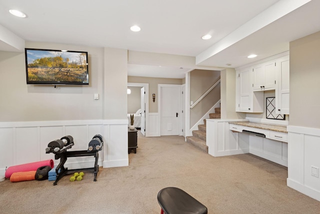 interior space with recessed lighting, a wainscoted wall, light carpet, and a decorative wall