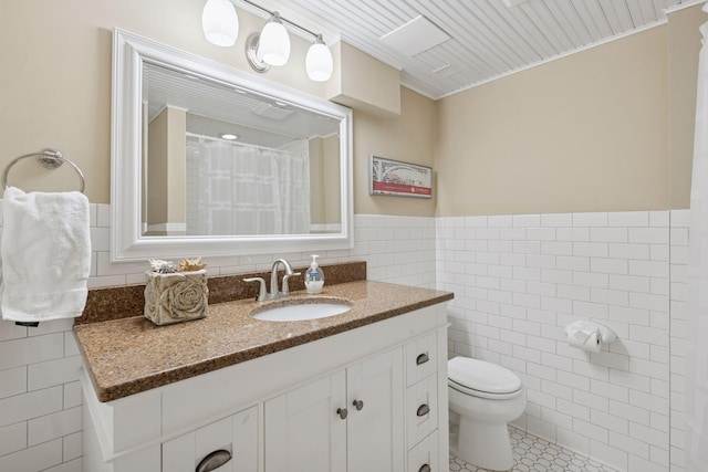 full bathroom with vanity, tile patterned flooring, wainscoting, tile walls, and toilet