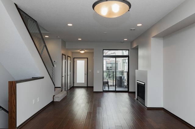 interior space with recessed lighting, dark wood-style flooring, a fireplace, baseboards, and stairs