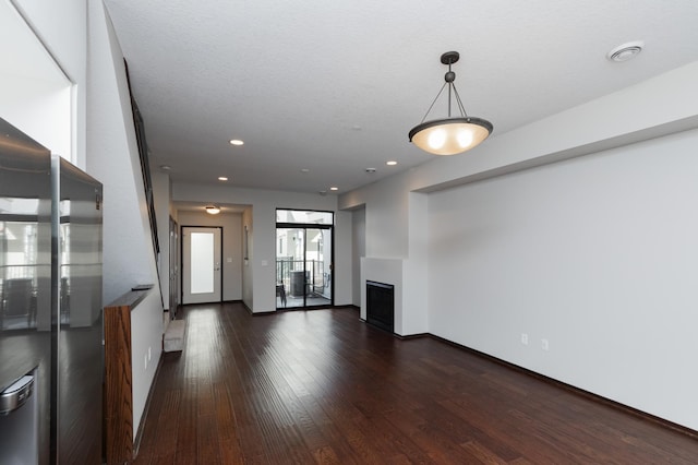 unfurnished living room with dark wood-style floors, recessed lighting, a fireplace, and baseboards