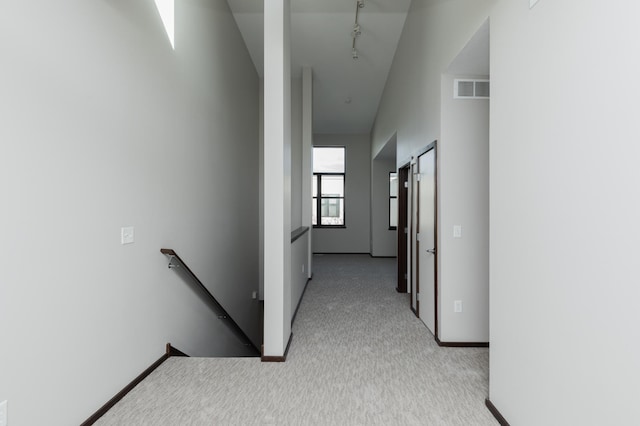 hall with light carpet, visible vents, baseboards, an upstairs landing, and track lighting