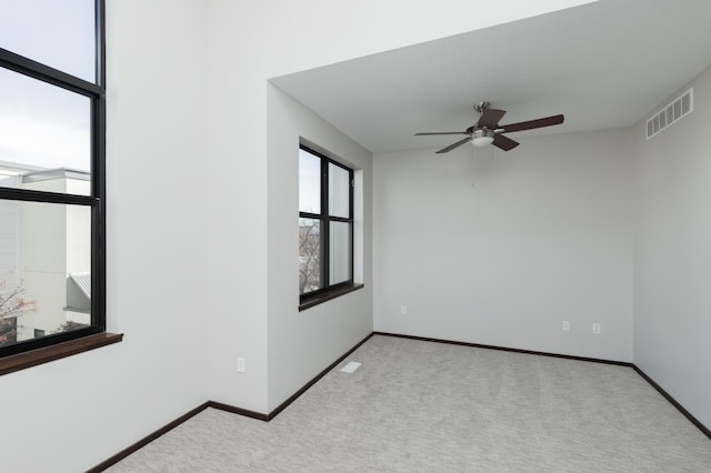 carpeted empty room featuring visible vents, ceiling fan, and baseboards