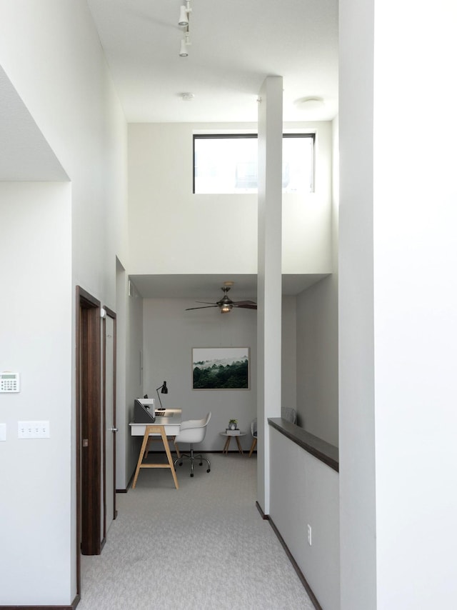 hallway featuring a towering ceiling and light colored carpet