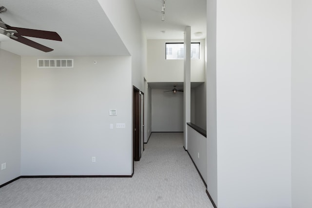 hall featuring light colored carpet, rail lighting, visible vents, and baseboards