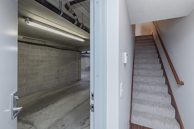 stairway featuring concrete flooring and concrete block wall