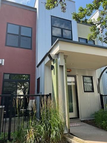 view of exterior entry with fence and stucco siding