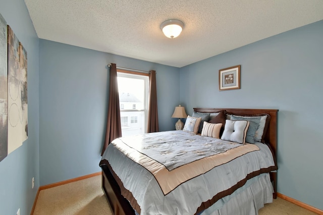 bedroom featuring light colored carpet, a textured ceiling, and baseboards