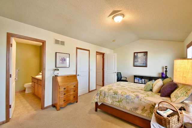 bedroom with visible vents, lofted ceiling, ensuite bathroom, a textured ceiling, and light carpet