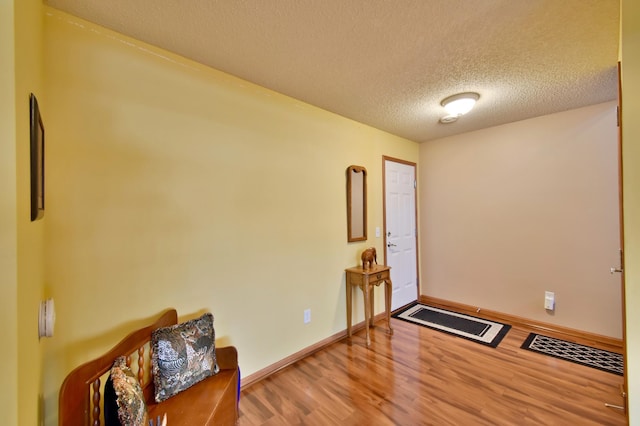 foyer entrance with a textured ceiling, baseboards, and wood finished floors