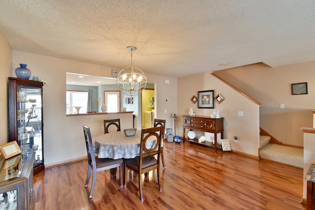 dining area featuring stairs, a textured ceiling, wood finished floors, and a chandelier