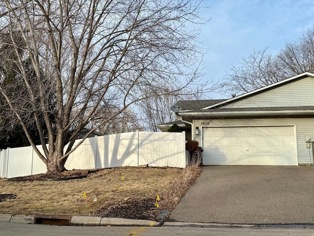 view of property exterior with aphalt driveway, an attached garage, fence, and a shingled roof