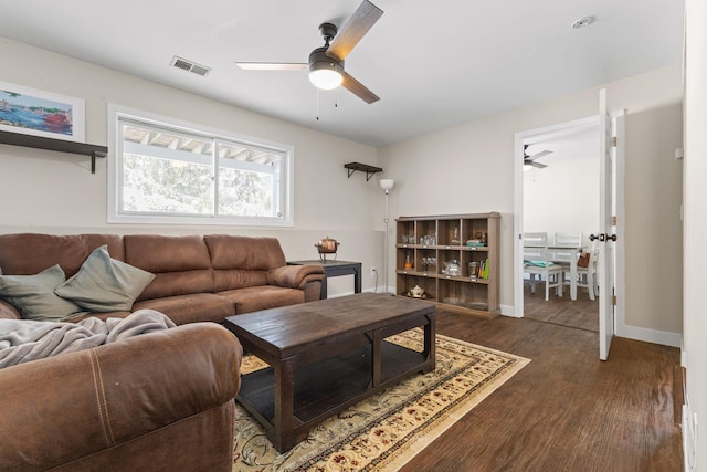 living area featuring a ceiling fan, dark wood-style floors, visible vents, and baseboards