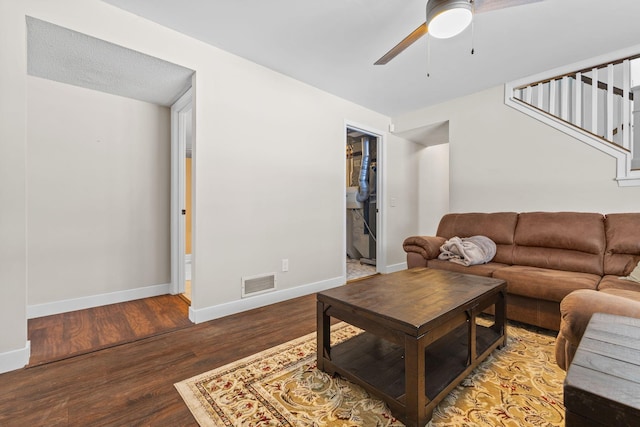 living room with visible vents, baseboards, stairs, wood finished floors, and a ceiling fan