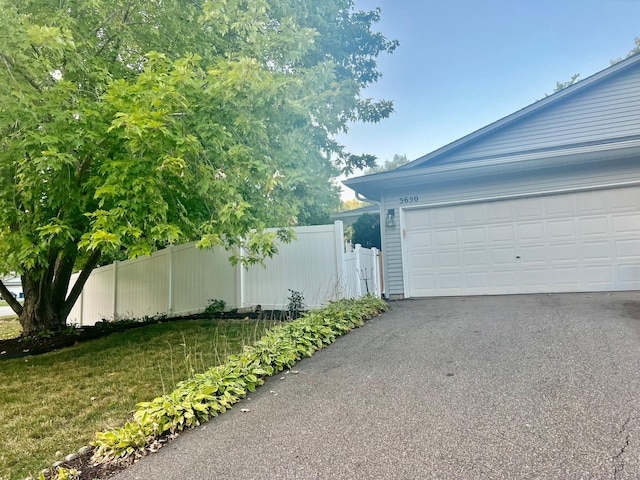 garage featuring aphalt driveway and fence