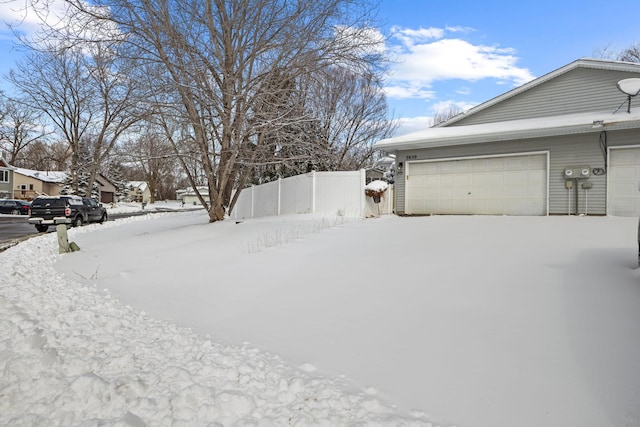 yard covered in snow with a garage and fence