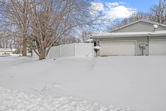 yard covered in snow with fence and a garage