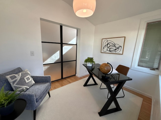 office space featuring lofted ceiling, light wood finished floors, and baseboards