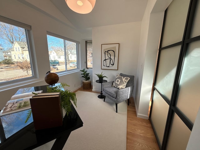 living area featuring light wood-type flooring, baseboards, and vaulted ceiling