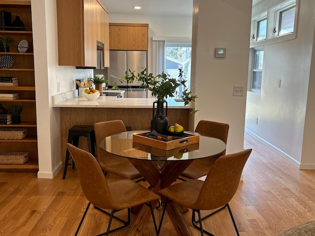 dining space with light wood finished floors, recessed lighting, and baseboards