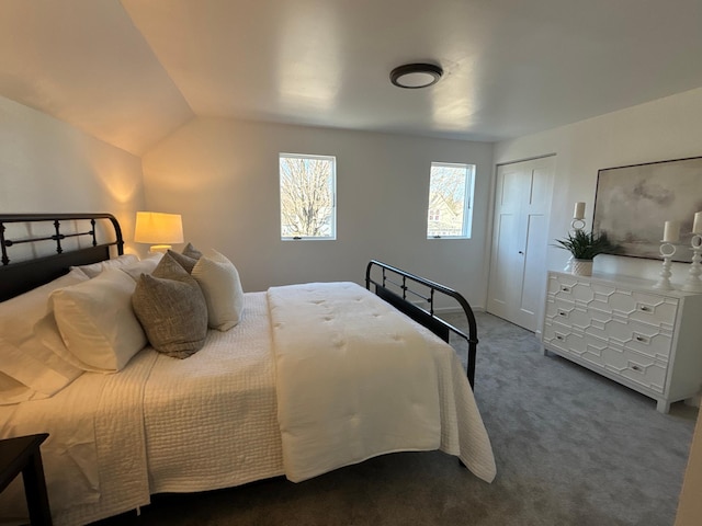 bedroom featuring lofted ceiling, a closet, and dark carpet