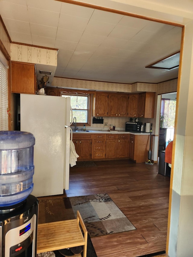 kitchen featuring dark wood-style flooring, black microwave, light countertops, freestanding refrigerator, and brown cabinets